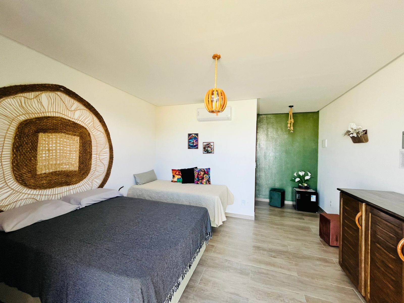 Quarto com cama de casal, cama auxiliar, frigobar e decoração verde